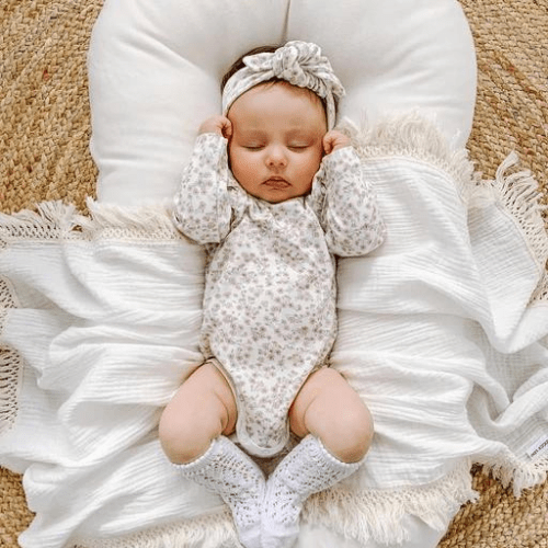 bébé dormant paisiblement dans un réducteur de lit bébé beige doux et moelleux sécurisant