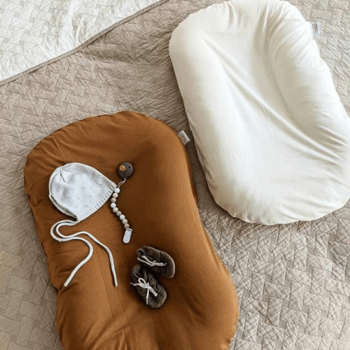 Réducteur de lit bébé couleur café avec bonnet, chaussons et coussin beige sur tissu matelassé
