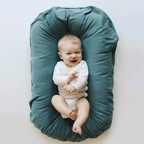 bébé allongé dans réducteur de lit bébé vert pour sommeil sécurisé confortable et apaisé