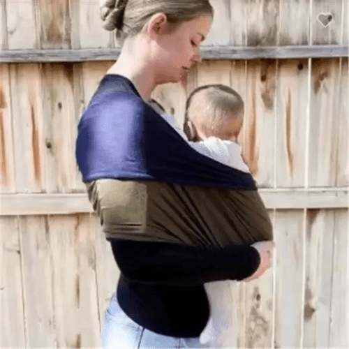 Mère portant bébé confortablement dans une écharpe de portage ergonomique et ajustable en tissu doux.