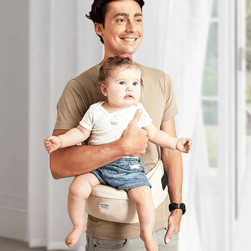 Homme portant un bébé dans un porte-bébé avec tabouret de taille beige, confort ergonomique et soutien optimal.